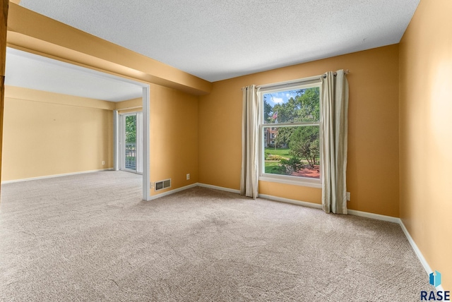 carpeted empty room with a textured ceiling