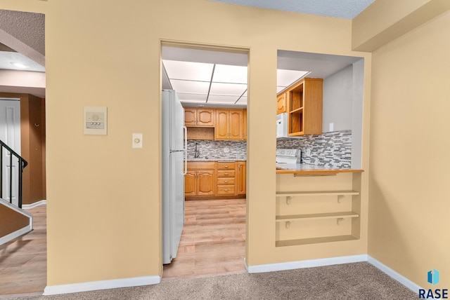 kitchen with white appliances, light carpet, and tasteful backsplash