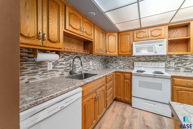 kitchen with white appliances, light hardwood / wood-style floors, tasteful backsplash, and sink