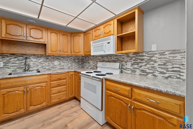 kitchen with white appliances, light wood-type flooring, decorative backsplash, and sink