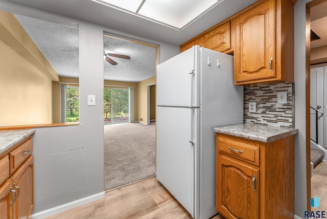 kitchen with light carpet, ceiling fan, white refrigerator, a textured ceiling, and backsplash