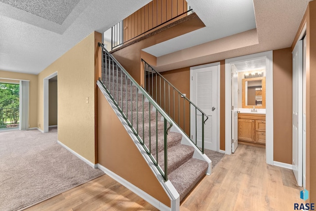 stairs featuring sink, a textured ceiling, and hardwood / wood-style floors