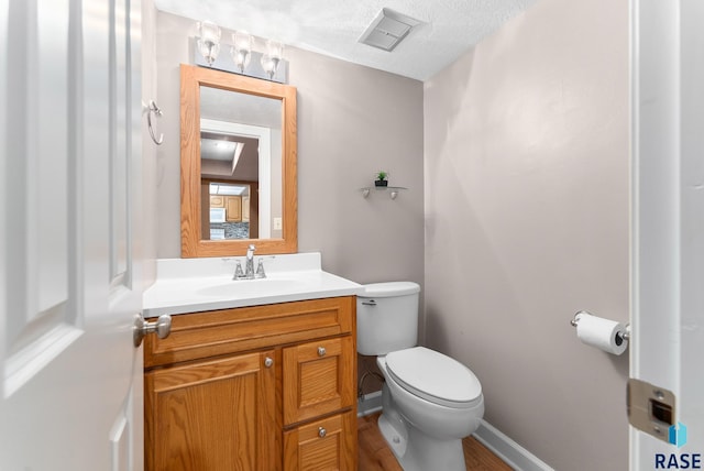 bathroom featuring toilet, vanity, a textured ceiling, and hardwood / wood-style floors