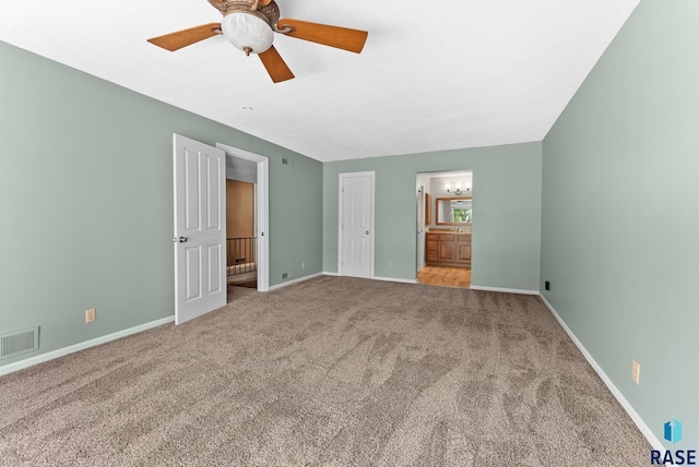 unfurnished bedroom with ensuite bath, ceiling fan, and light carpet