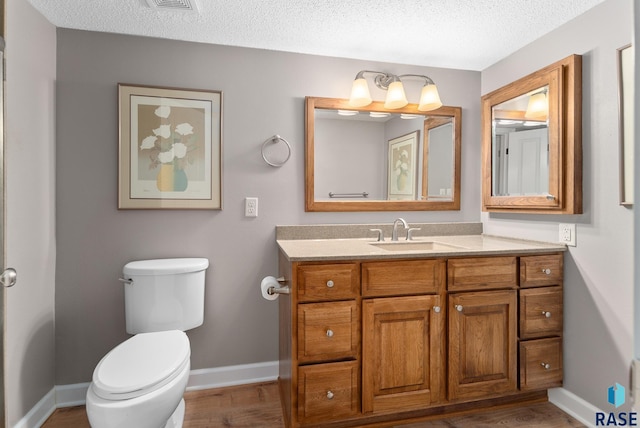 bathroom with toilet, hardwood / wood-style flooring, a textured ceiling, and vanity