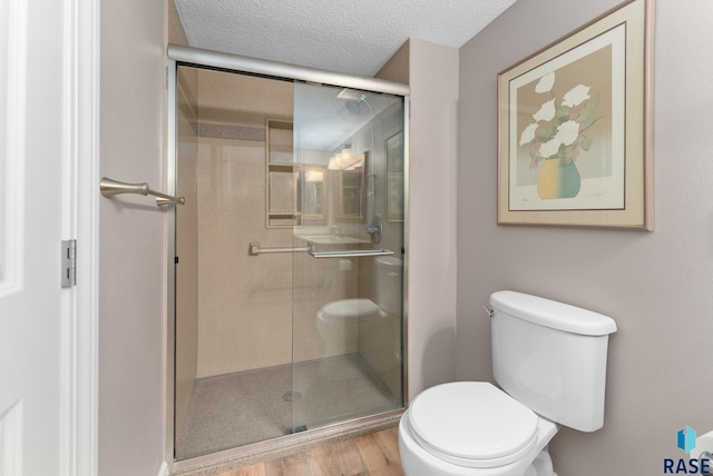 bathroom featuring toilet, a textured ceiling, a shower with door, and hardwood / wood-style floors