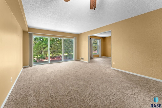 unfurnished room featuring ceiling fan, light colored carpet, and a textured ceiling