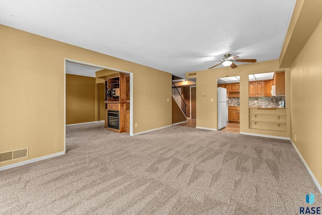 unfurnished living room featuring ceiling fan and light colored carpet