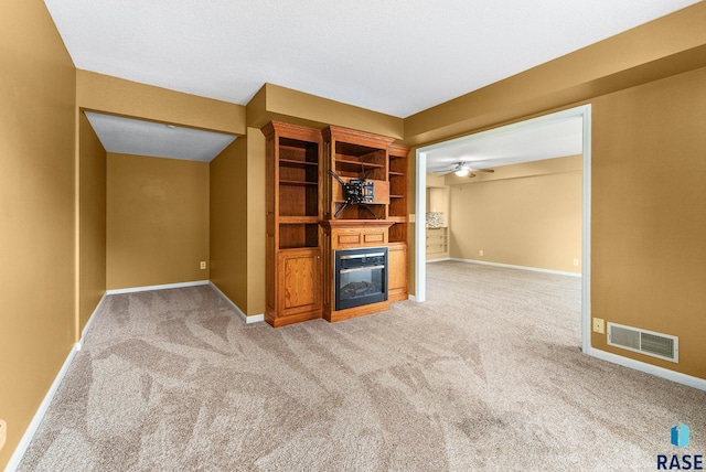 unfurnished living room with ceiling fan and carpet