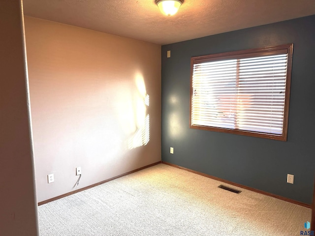 carpeted empty room with a textured ceiling