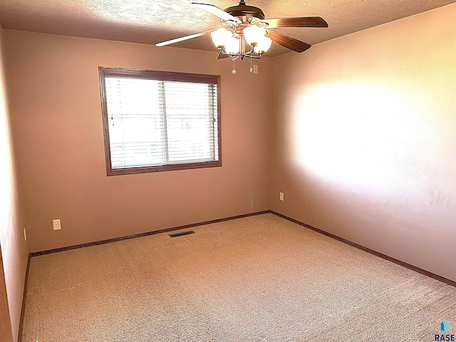 empty room featuring a textured ceiling, carpet floors, and ceiling fan