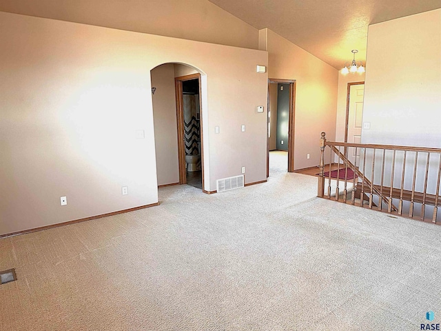 unfurnished room featuring high vaulted ceiling, a chandelier, and carpet