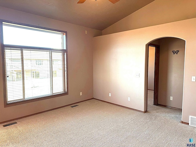 empty room with light colored carpet, ceiling fan, and vaulted ceiling