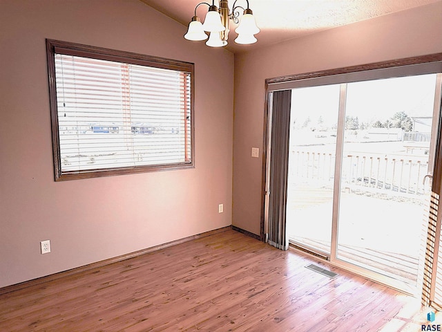 unfurnished room featuring vaulted ceiling, a chandelier, and wood-type flooring