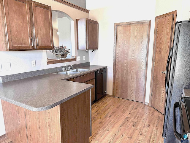 kitchen with kitchen peninsula, light hardwood / wood-style flooring, black appliances, and sink