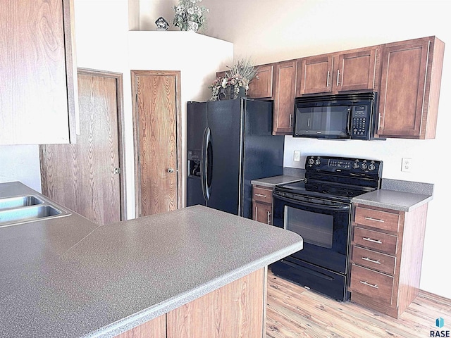 kitchen with light hardwood / wood-style floors, black appliances, and kitchen peninsula