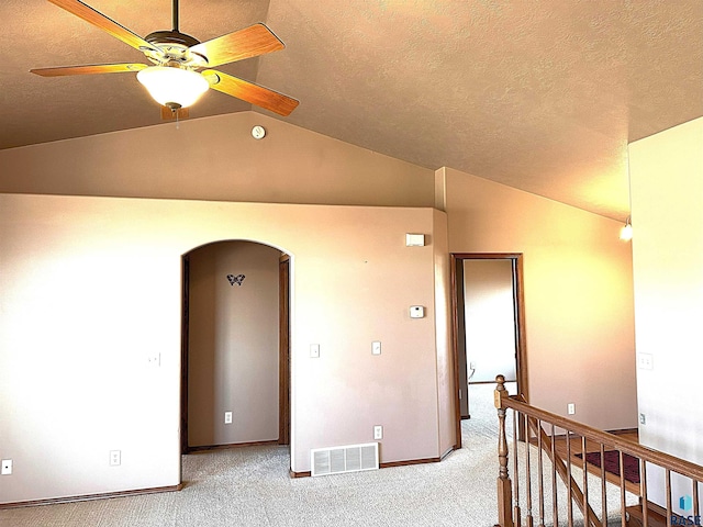 spare room with ceiling fan, carpet, lofted ceiling, and a textured ceiling