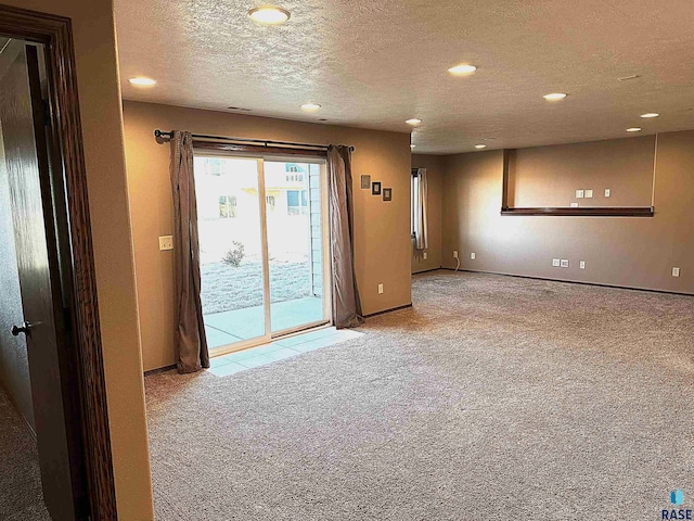 spare room with a textured ceiling and light carpet