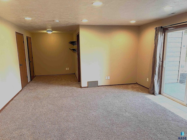 spare room featuring a textured ceiling and light carpet