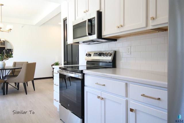 kitchen featuring stainless steel appliances, pendant lighting, and white cabinetry