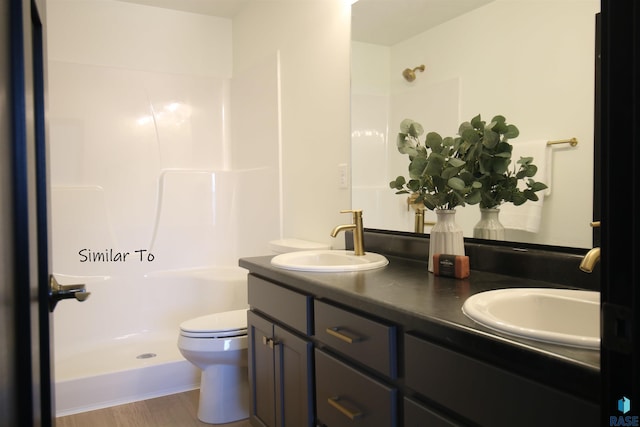 bathroom featuring toilet, wood-type flooring, walk in shower, and vanity