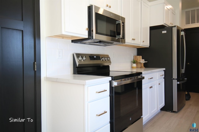 kitchen featuring white cabinets, tasteful backsplash, light hardwood / wood-style flooring, and appliances with stainless steel finishes