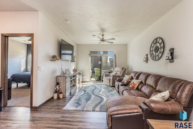 living room featuring ceiling fan and dark wood-type flooring