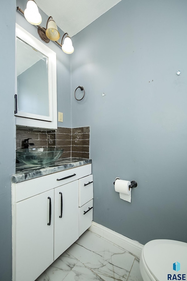 bathroom featuring toilet, backsplash, and vanity