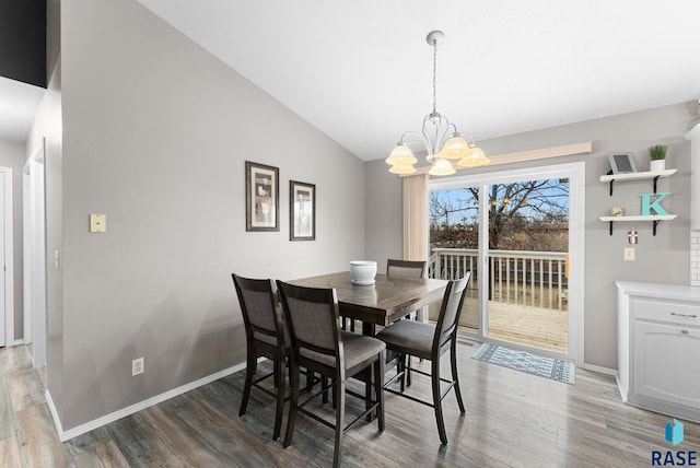 dining room featuring a notable chandelier, vaulted ceiling, and hardwood / wood-style flooring