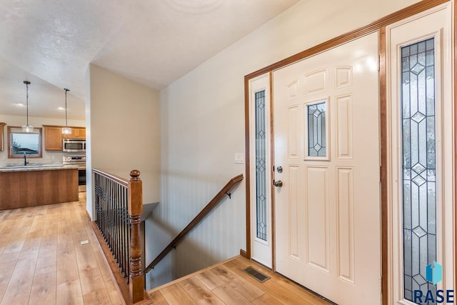 foyer entrance with light wood-type flooring and sink