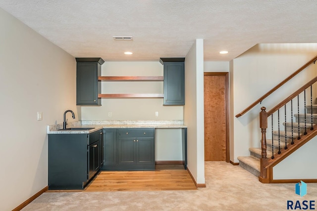 kitchen with sink, a textured ceiling, and light carpet