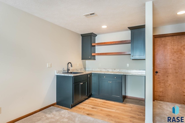 kitchen with a textured ceiling, light hardwood / wood-style floors, and sink