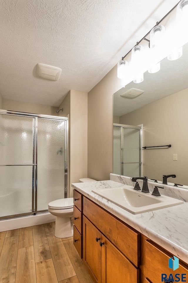 bathroom featuring toilet, a shower with shower door, and vanity