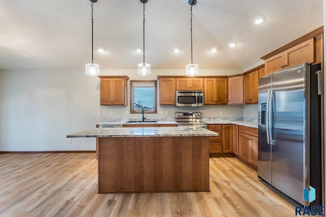 kitchen featuring appliances with stainless steel finishes, light hardwood / wood-style floors, pendant lighting, a kitchen island, and sink