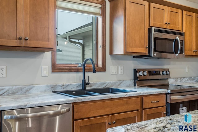 kitchen with sink, stainless steel appliances, and light stone counters