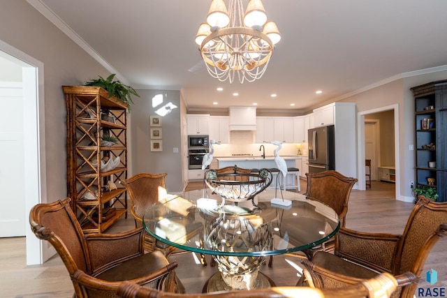 dining space featuring ornamental molding, light hardwood / wood-style flooring, sink, and a chandelier