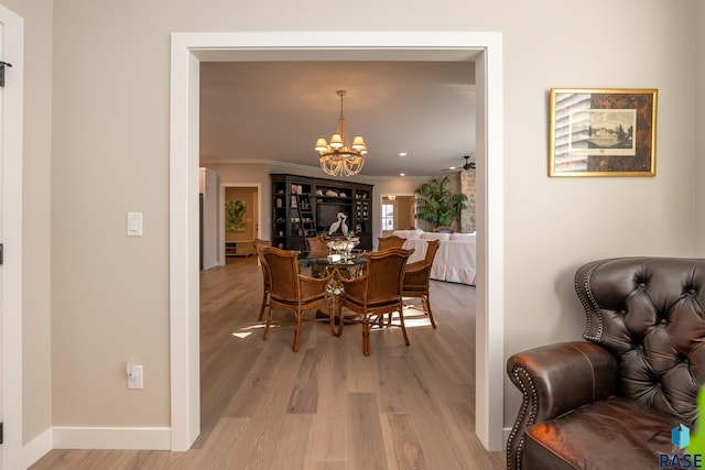 dining area with an inviting chandelier, crown molding, and light hardwood / wood-style flooring