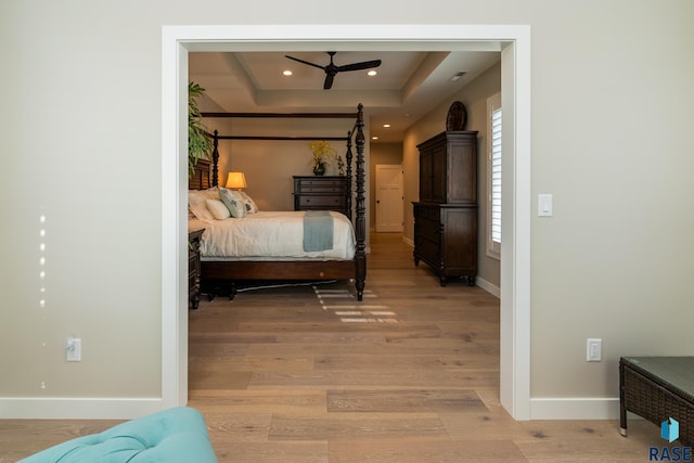 bedroom with a tray ceiling and light hardwood / wood-style flooring