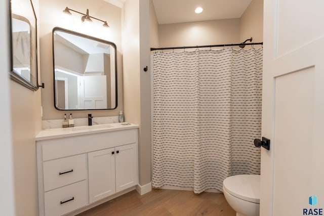 bathroom with toilet, hardwood / wood-style flooring, curtained shower, and vanity