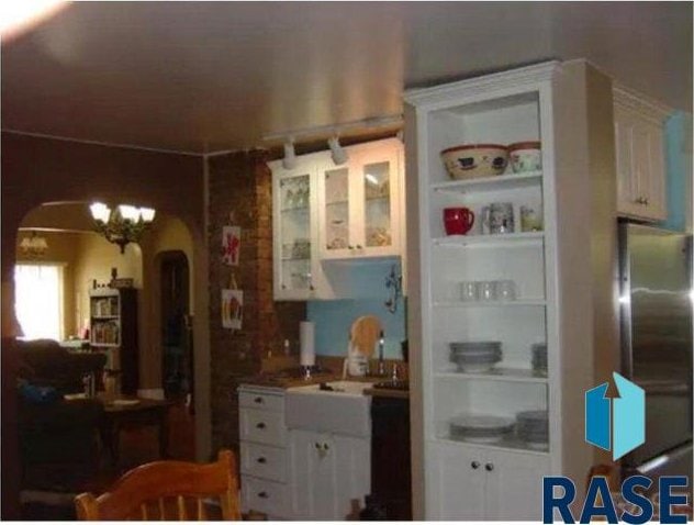 kitchen with white cabinets, stainless steel fridge, sink, and an inviting chandelier