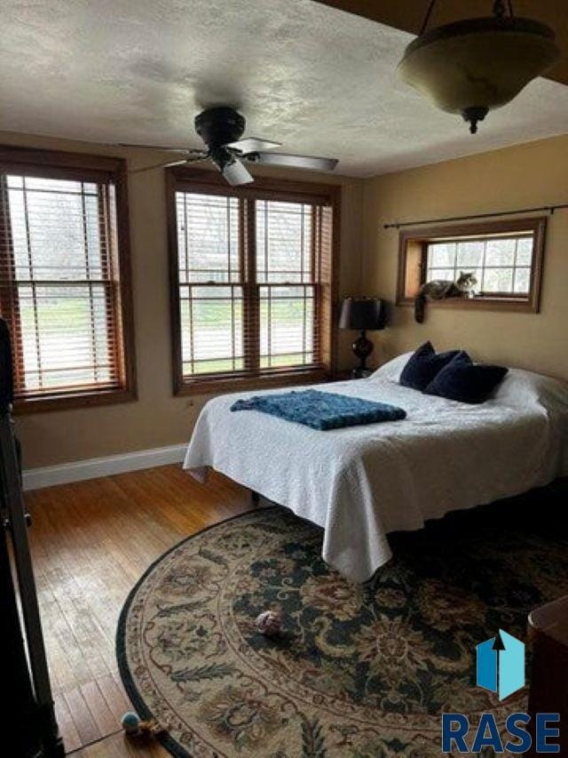 bedroom with ceiling fan, wood-type flooring, and a textured ceiling