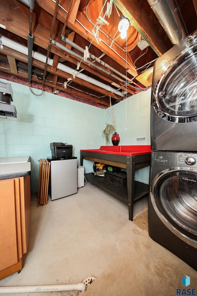 basement featuring stacked washing maching and dryer and refrigerator