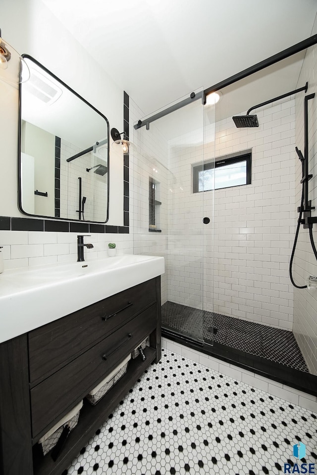 bathroom with a shower with shower door, vanity, and tasteful backsplash