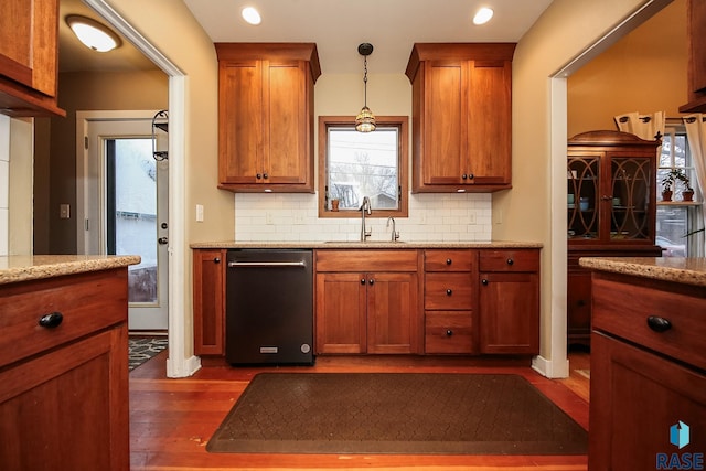 kitchen featuring light stone counters, backsplash, dishwashing machine, and sink