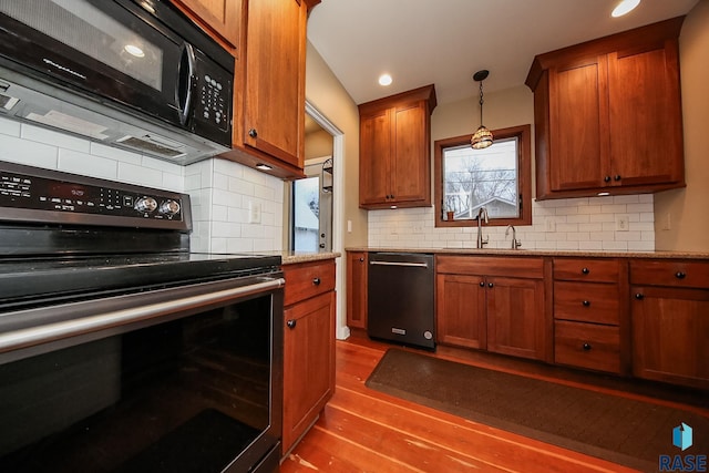 kitchen with light stone countertops, appliances with stainless steel finishes, decorative light fixtures, sink, and backsplash