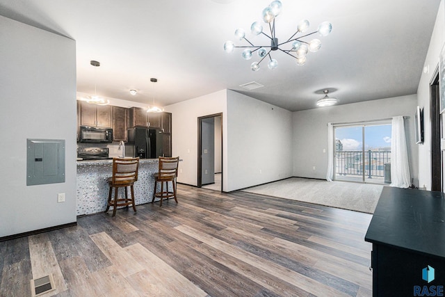 kitchen with electric panel, a kitchen breakfast bar, a peninsula, black appliances, and a notable chandelier