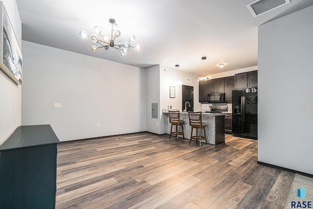 kitchen with a peninsula, black appliances, visible vents, and wood finished floors