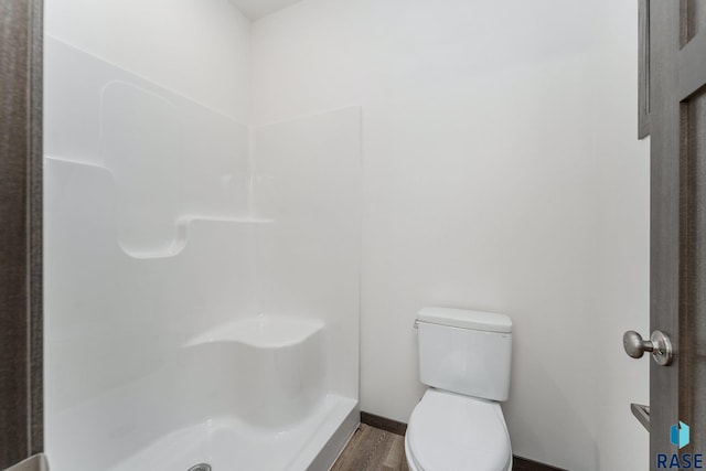 bathroom featuring toilet, hardwood / wood-style flooring, and walk in shower