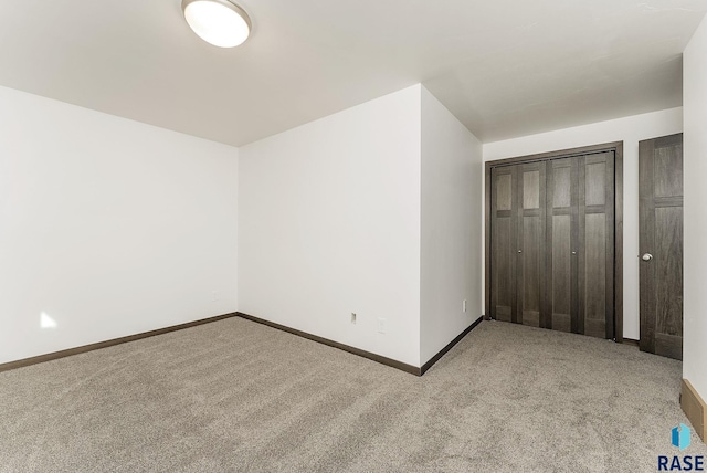 unfurnished bedroom featuring a closet and light colored carpet