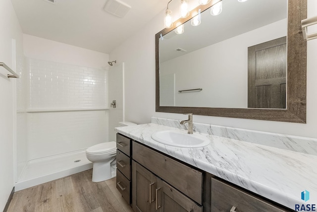 bathroom featuring toilet, walk in shower, hardwood / wood-style floors, and vanity